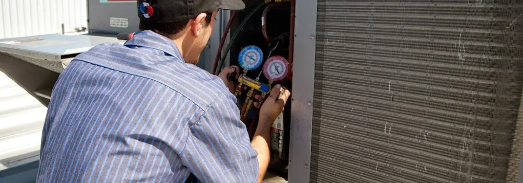 HVAC technician servicing a condenser unit in Alexandria